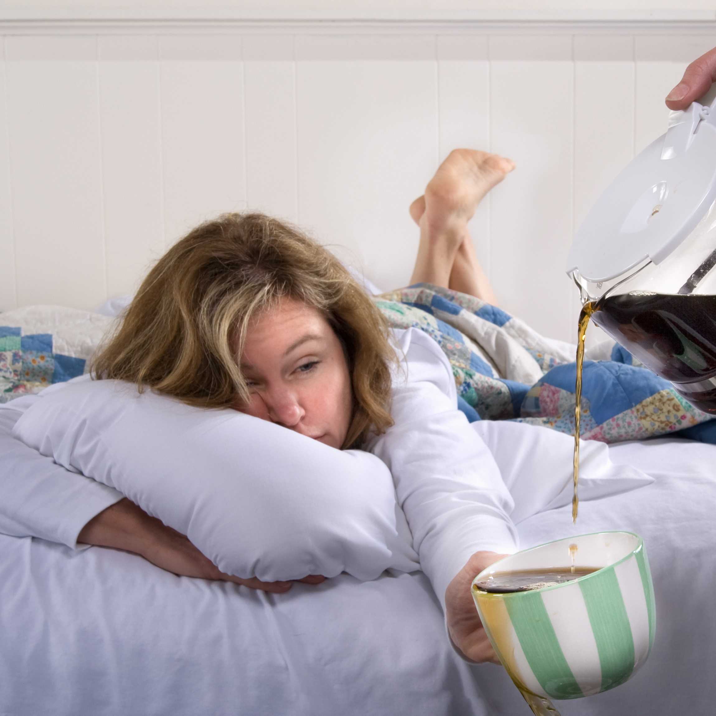 Woman in bed desperate for a cup of coffee. People Need Coffee Not Junk Food.